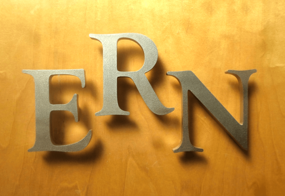 Buchstaben aus 4 mm Aluminium, Eiche natur, Logo eingefräst.